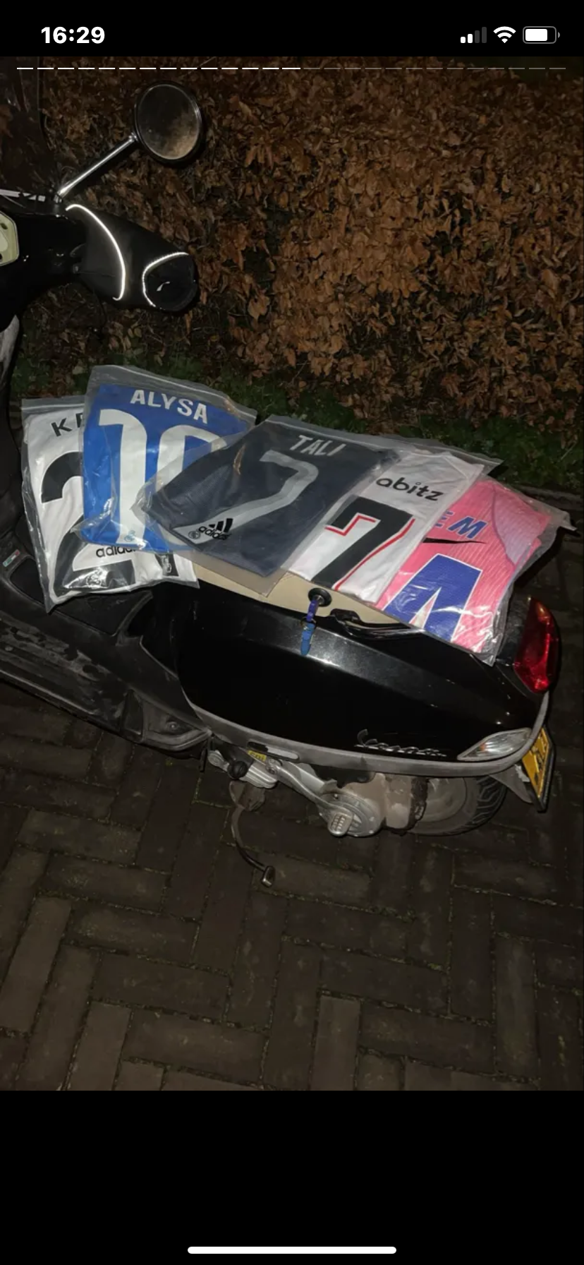 Klantfoto van meerdere ingepakte shirts op een scooter